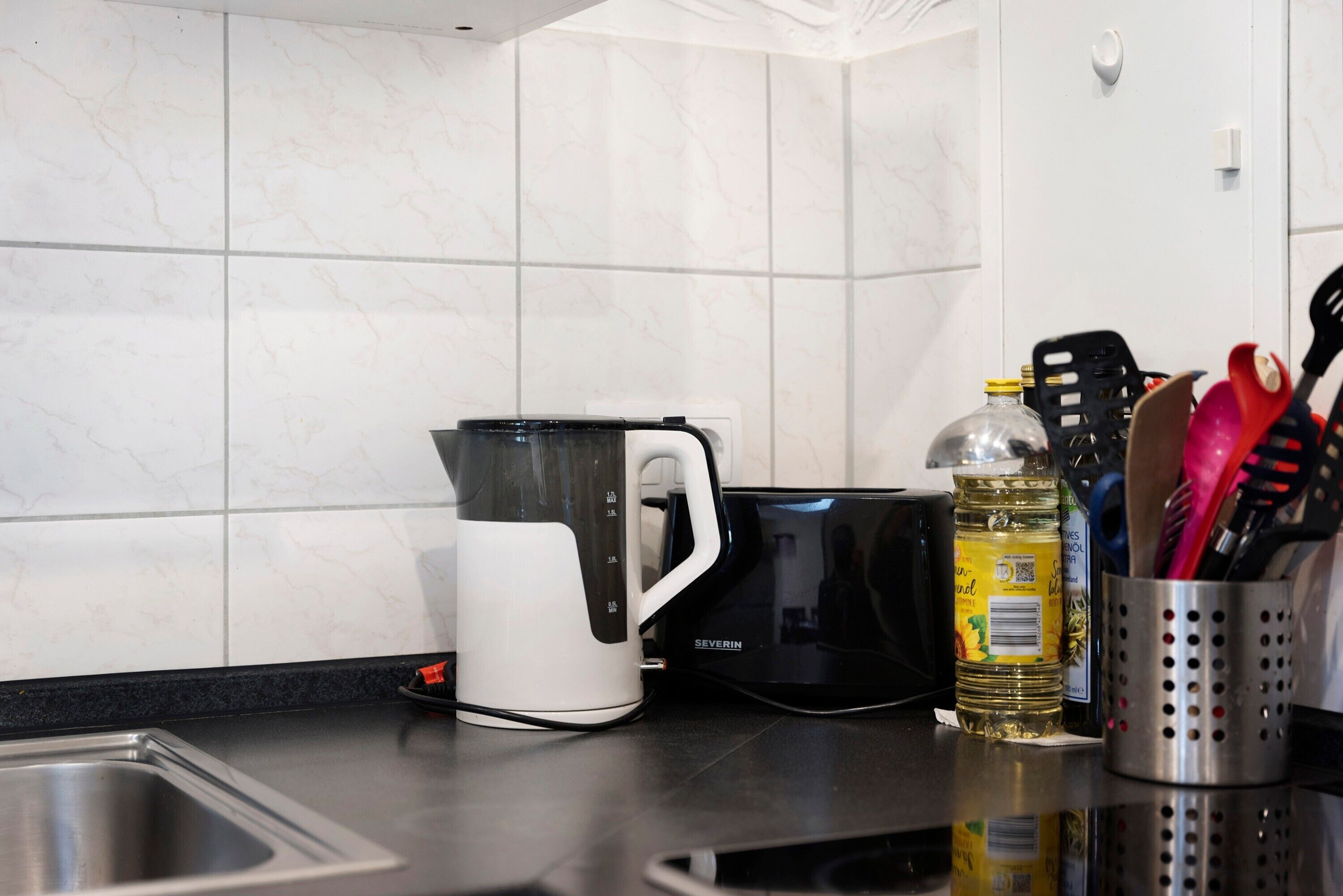 Una cucina con una macchina da caffè, un frullatore e una bottiglia d'olio sul piano di lavoro.