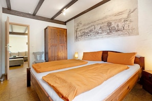 A bedroom with two beds, wooden headboard, a large painting on the wall, and a wooden wardrobe.