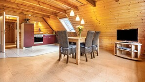 Un intérieur chaleureux en bois, comprenant un coin repas, une cuisine et un meuble pour la télévision.