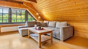 Un intérieur en bois avec un canapé, une table et une fenêtre donnant sur un espace verdoyant.