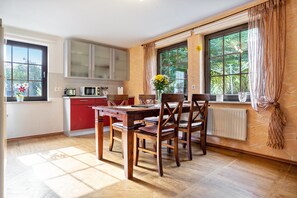 A kitchen with a dining table, chairs, and a window with curtains. - Holiday Apartment 'Müritz, 80sqm' with Shared Terrace, Shared Garden and Wi-Fi (Malchin)