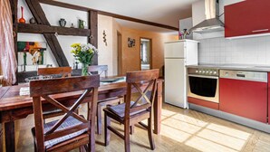 Una cocina con sillas de madera, una mesa de comedor y un electrodoméstico rojo.