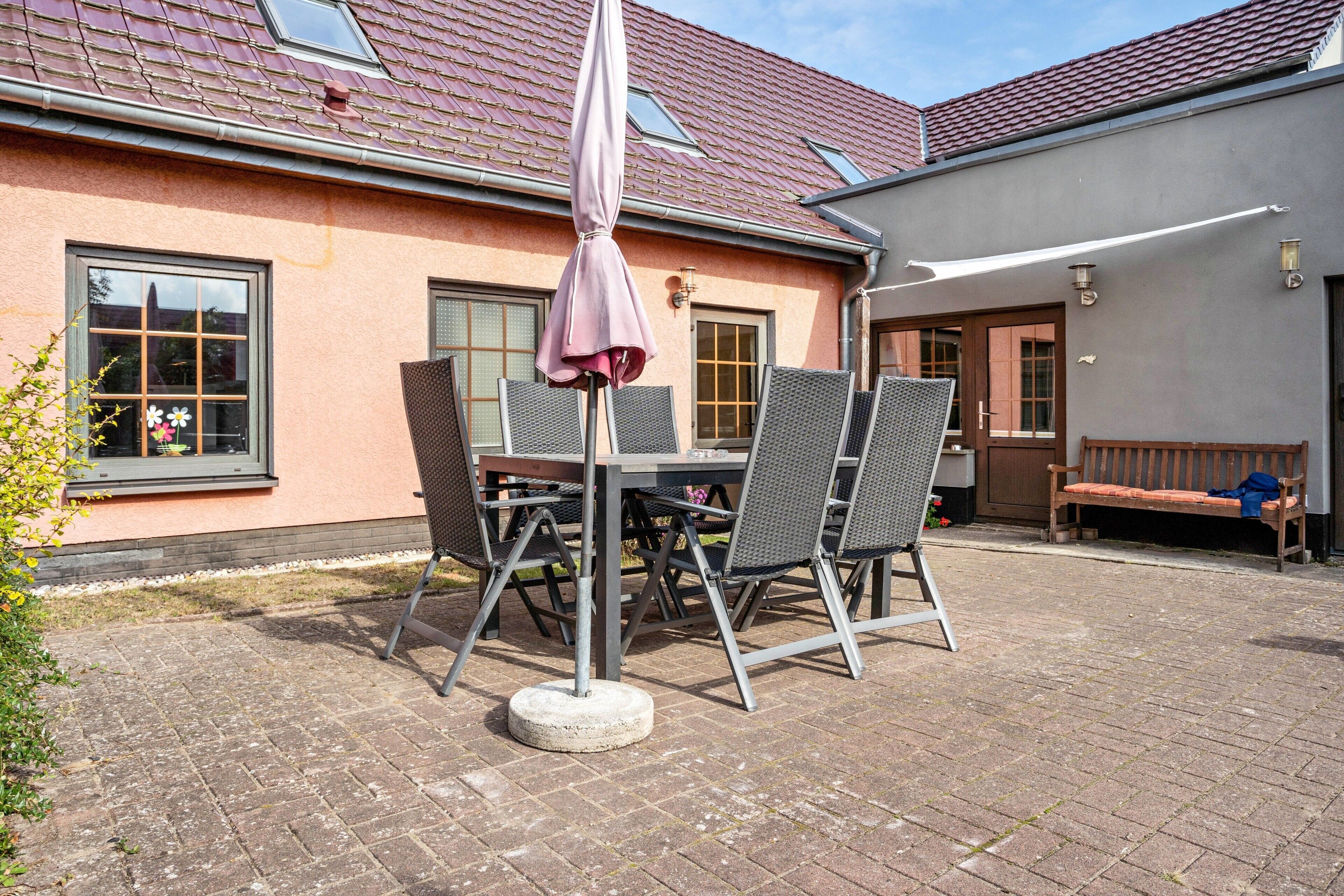 Une terrasse extérieure avec une table et des chaises, un banc et un parasol.