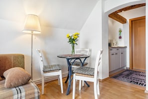 A dining area with a table, chairs, a lamp, and a vase with flowers.