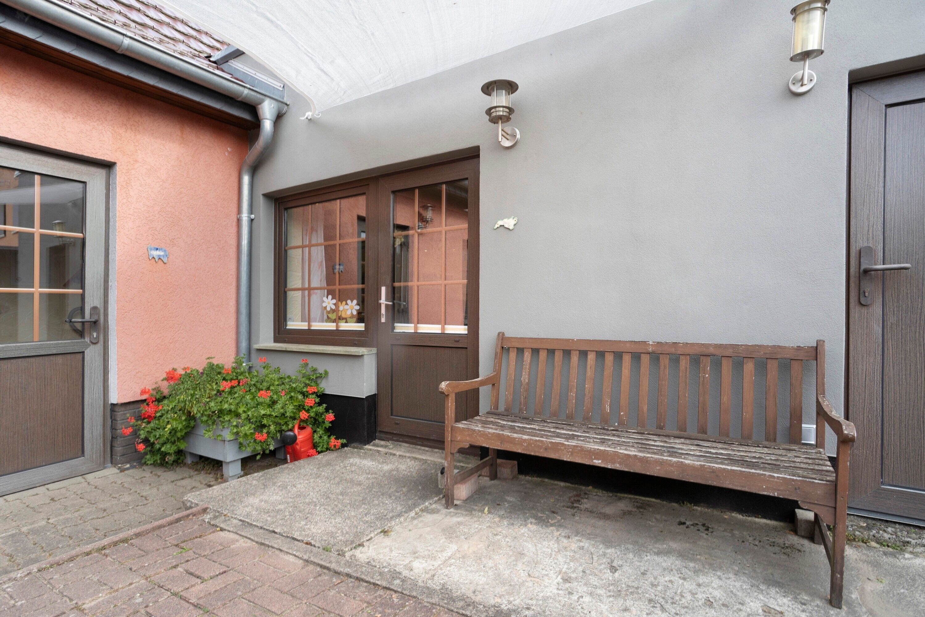 Un banc se trouve devant un bâtiment qui possède une porte et des fenêtres.