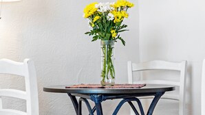 Una mesa con un jarrón de flores, una lámpara y sillas blancas.