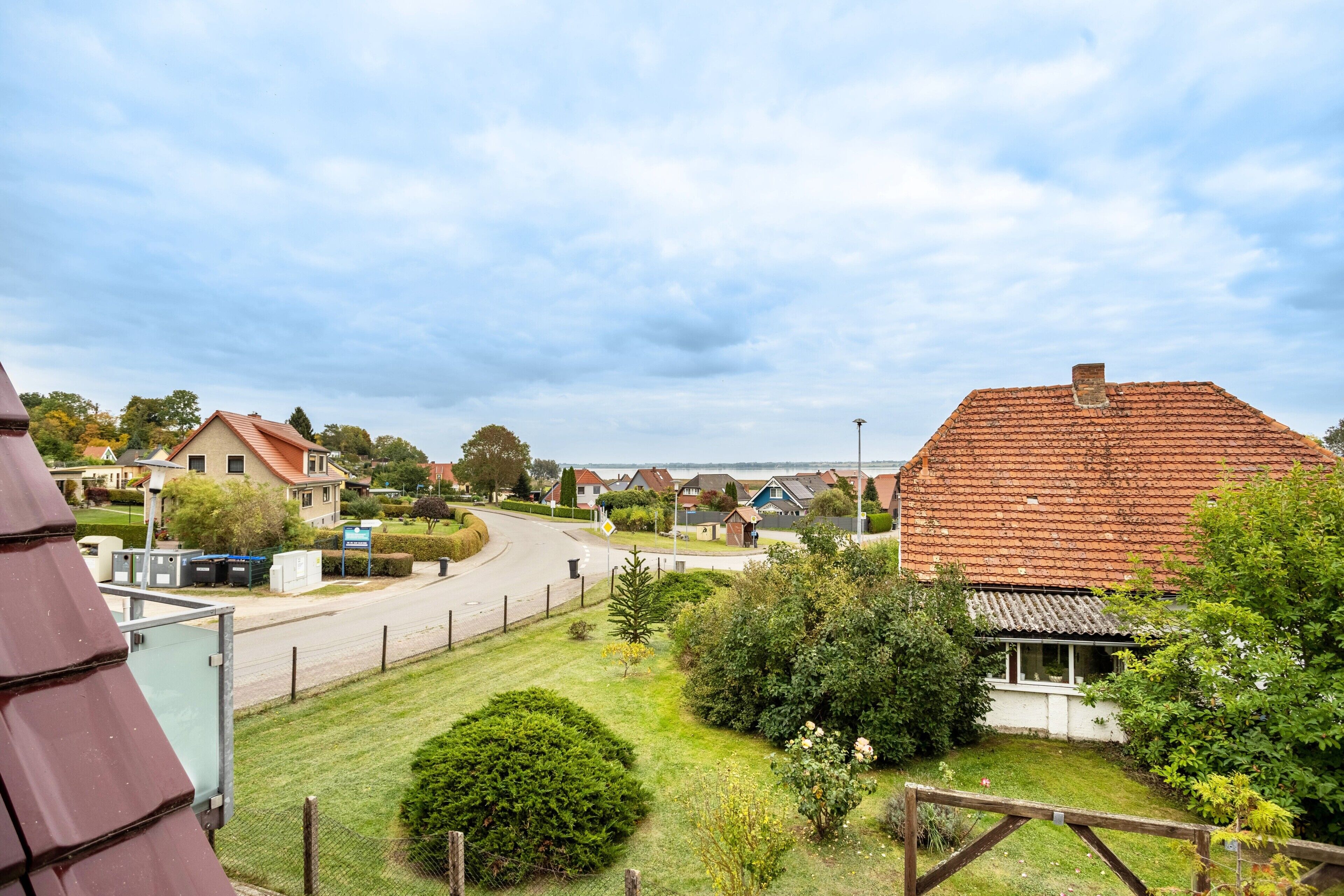 A residential area with houses, a road, and a grassy area with a fence.