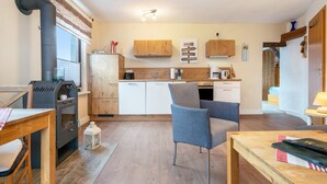 Een moderne keuken met houten kastjes, een ingebouwde kookplaat en een eethoek met een tafel en stoelen.