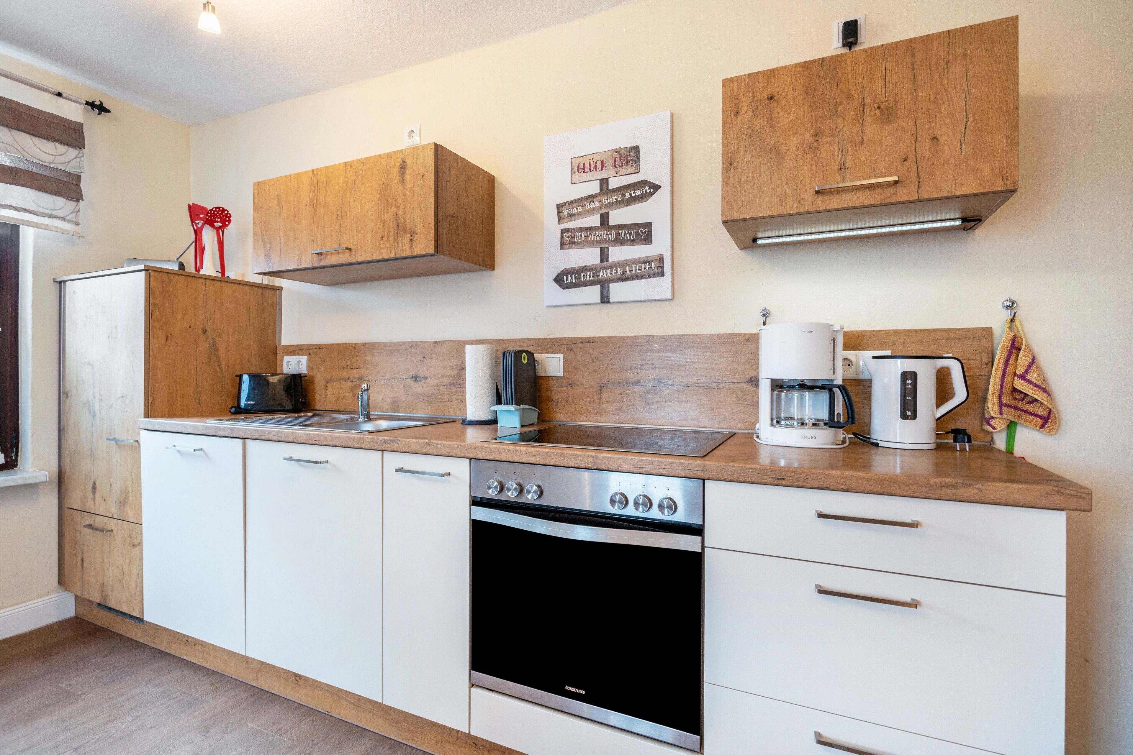Eine moderne Küche mit Holzausstattung, Backofen, Kaffeemaschine und einer an der Wand befestigten Beschilderung.