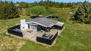 A modern house with a large patio, a covered outdoor seating area, and a chimney. - "Rieke" - 2km from the sea by Interhome (Blokhus)