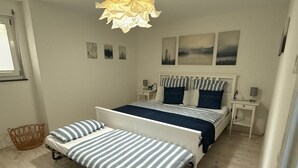 Une chambre avec deux lits, une table de chevet avec une lampe, un luminaire suspendu et des œuvres d’art murales.