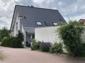 A residential building with a sloped roof, a visible entrance, and a paved driveway.