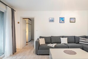 A modern living room with a grey sofa, a white coffee table, and three framed pictures on the wall.