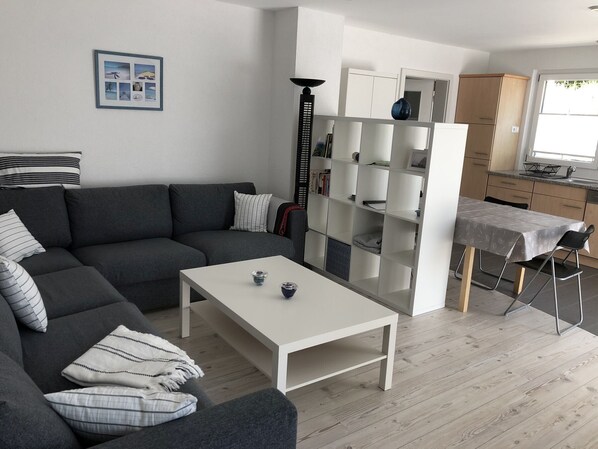 A modern living room with a grey sofa, a white coffee table, and a bookshelf.