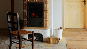 A room with a fireplace, a wooden chair, a stone floor, and a wooden door. - Holiday Home 'Bernau' with Mountain View, Private Terrace and Wi-Fi (Bernau im Schwarzwald)