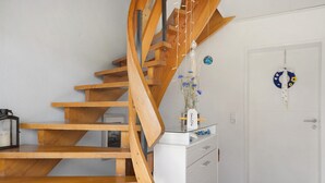 A wooden staircase leading to a landing with a glass-top table holding a vase of flowers.