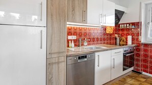 A kitchen with white cabinets, a Bosch dishwasher, a red patterned backsplash, and a wooden countertop.