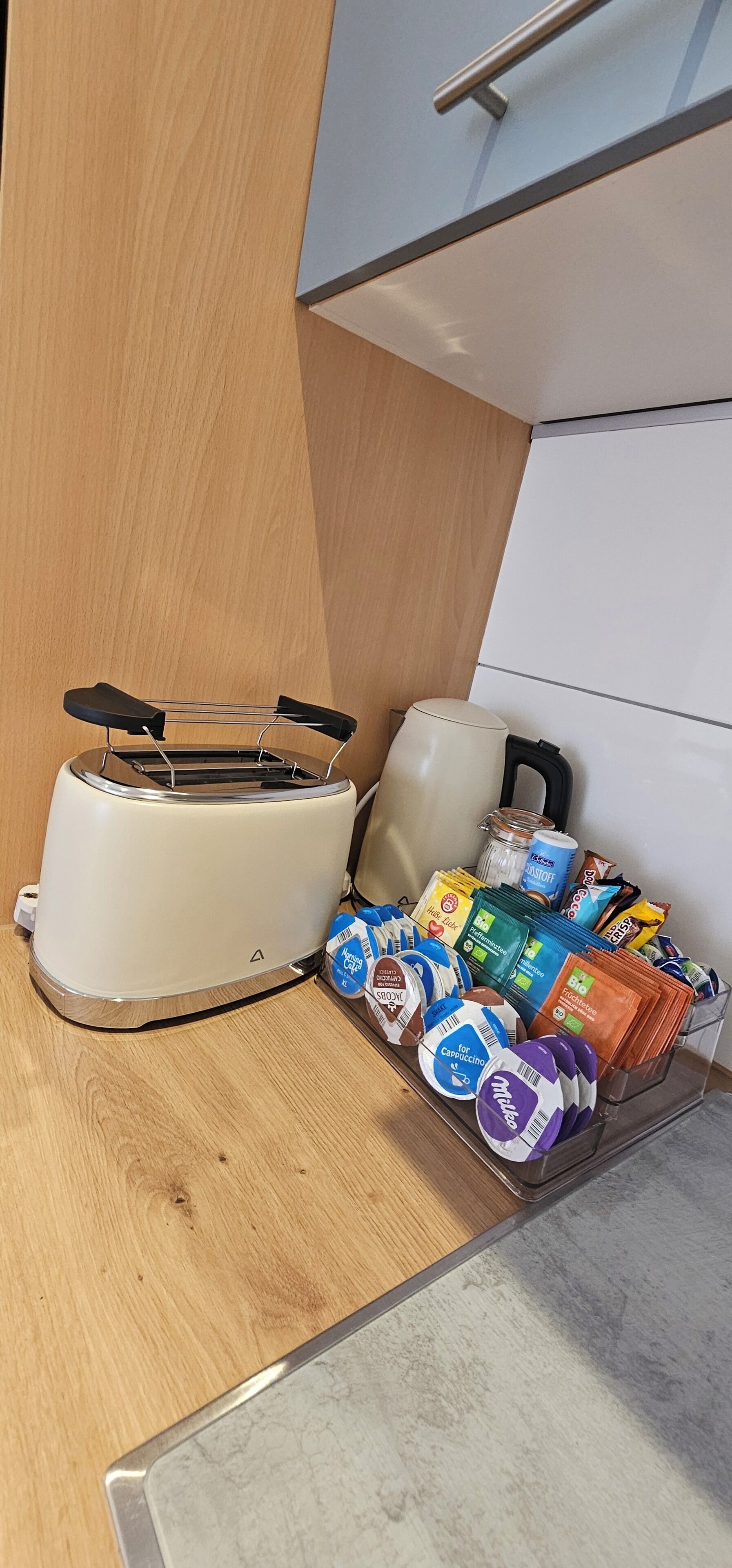 Een keuken met een broodrooster, een waterkoker en diverse verpakte producten op het aanrecht.