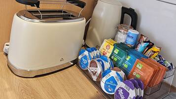 Een keuken met een broodrooster, een waterkoker en diverse verpakte producten op het aanrecht.