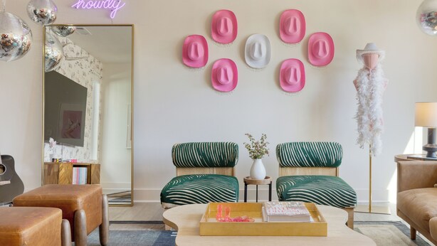 A living room with a mirrored wall, a neon sign, and a collection of hats.