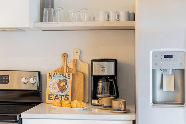 Una cocina con estufa, cafetera, dispensador de agua y un letrero que dice 'Nashville Eats'.