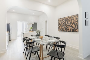 Un comedor moderno con una mesa de vidrio, sillas negras y un interior blanco.
