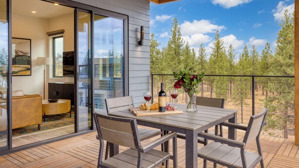 An outdoor patio with a wooden table set for dining, a sofa, and a glass door leading to an interior space. - 2 Units | Minutes to Old Bend, Deck + Hot Tub | 1204 Skyline Ranch by AvantStay (Bend)