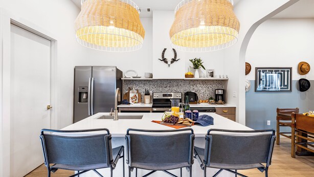 Une cuisine moderne dotée d’un îlot central, de deux suspensions et d’un coin repas avec trois chaises.
