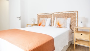 Ein Schlafzimmer mit einem großen Bett, zwei Nachttischen, einem Holznachttisch und einem kleinen Tisch mit einer Lampe.