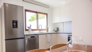 Eine moderne Küche mit Edelstahlgeräten, einem Geschirrspüler und einem Fenster für natürliches Licht.