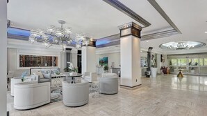 A spacious lobby with modern furniture, a large chandelier, and a view of the outside.