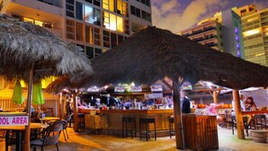 An outdoor bar area with thatched umbrellas, a pool table, and a sign indicating a school area. - Tropical Retreat with Pool, Spa & Resort-Style Amenities (Fort Lauderdale)