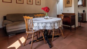 Comedor con una mesa redonda cubierta por un mantel de encaje blanco, rodeado de sillas de madera.