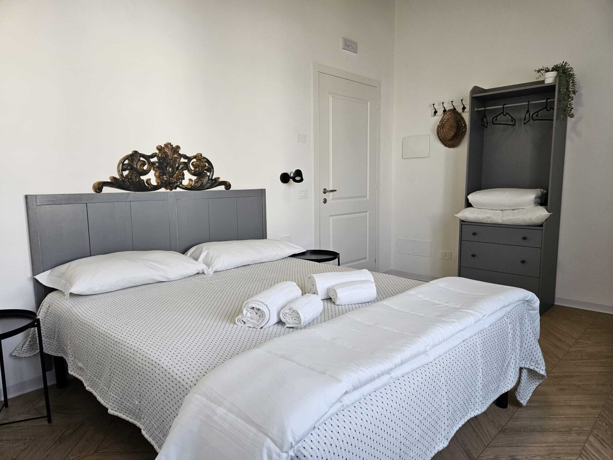 Quarto bem organizado com uma cama grande, mesa de cabeceira, guarda-roupa e porta.