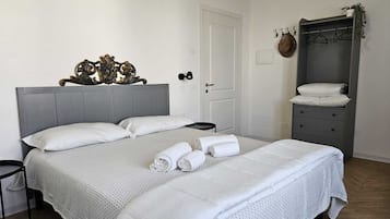 Quarto bem organizado com uma cama grande, mesa de cabeceira, guarda-roupa e porta.