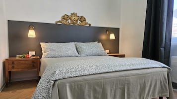 Una cama bien hecha con ropa de cama estampada, dos mesitas de noche con lámparas y un adorno decorativo sobre la cama.