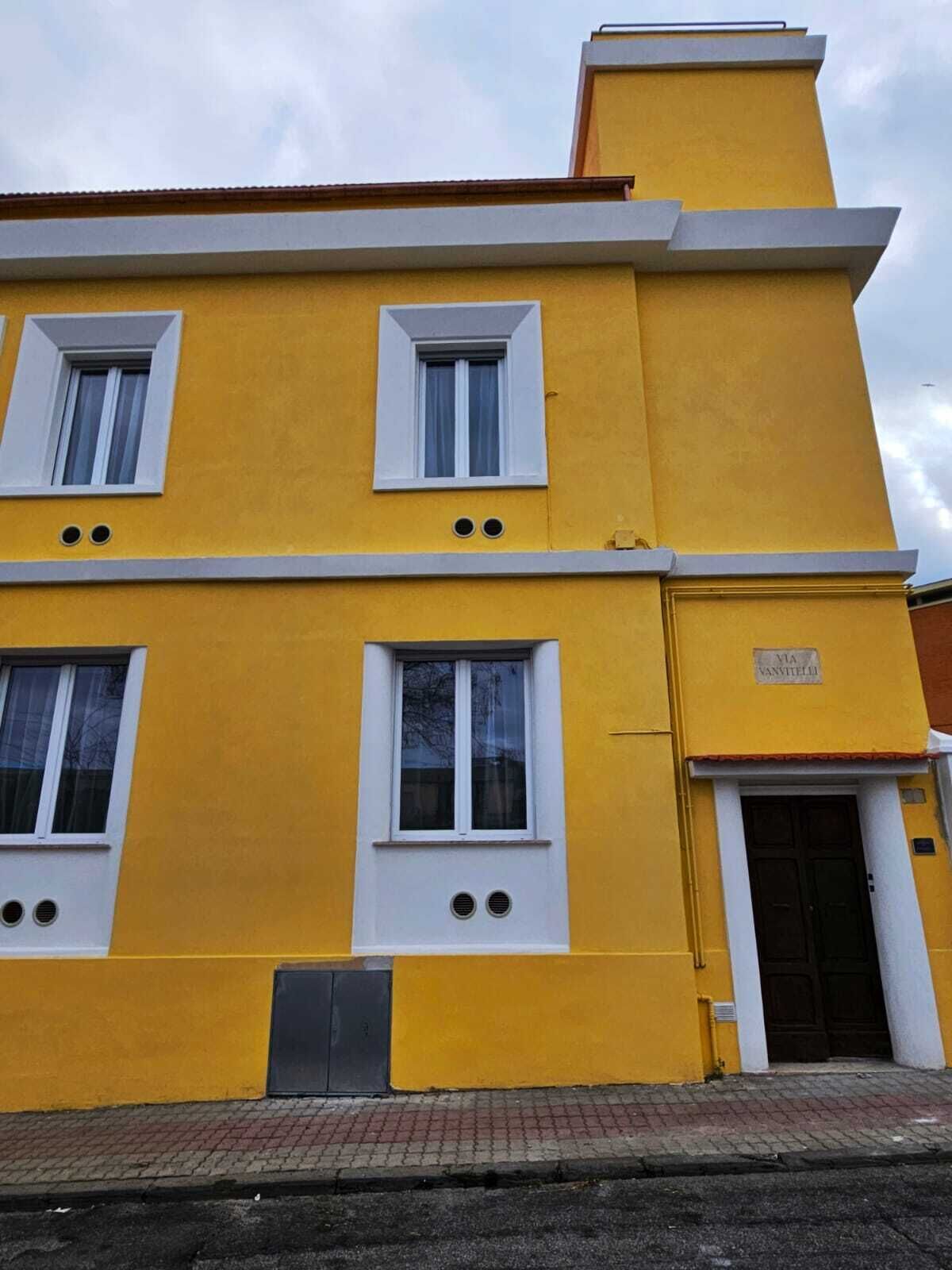 Un edificio amarillo con tres ventanas y una puerta.