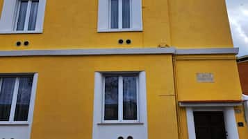 Un edificio amarillo con tres ventanas y una puerta.