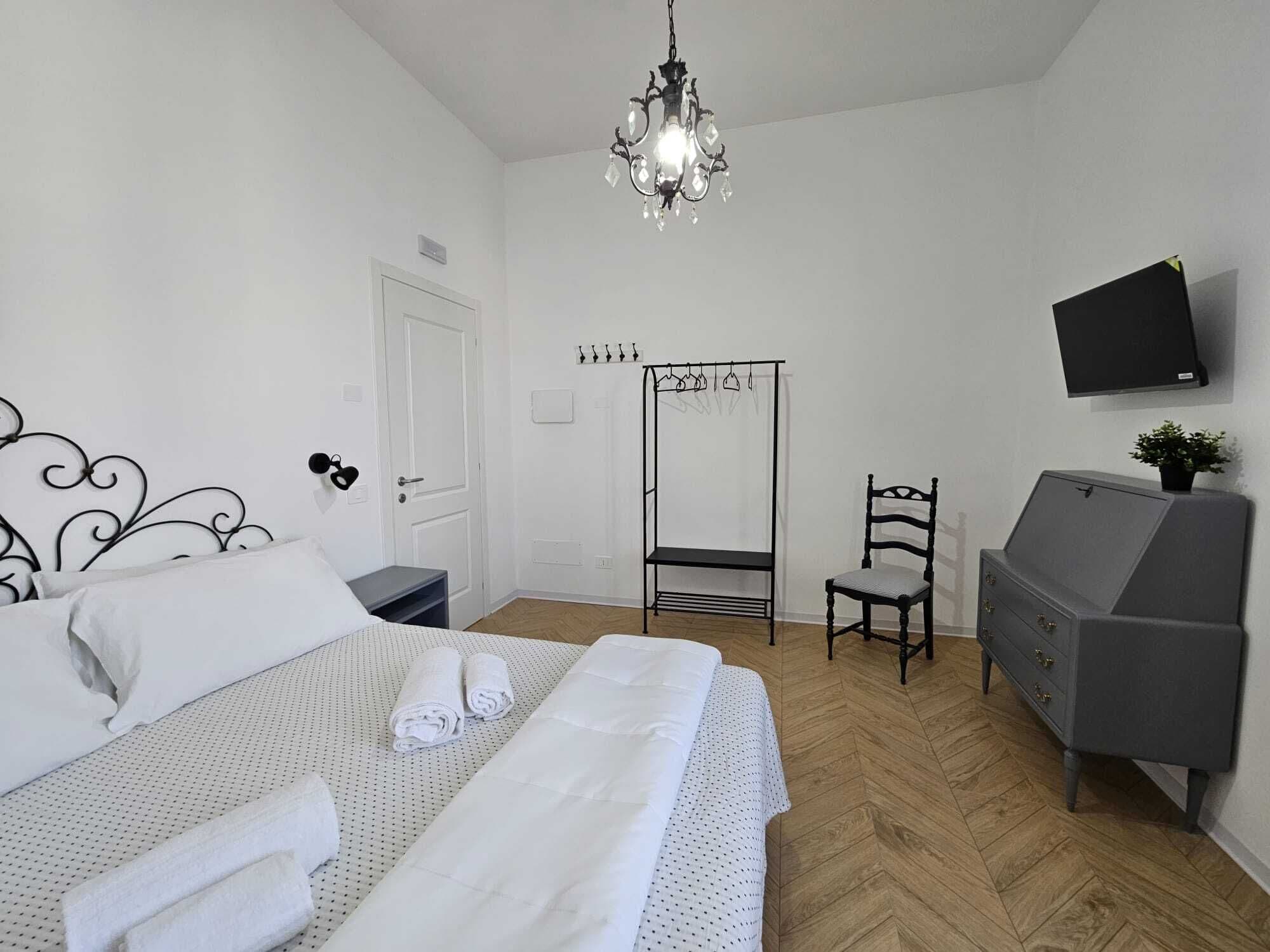 Un dormitorio con cama, cómoda, silla, espejo, televisor y candelabro.