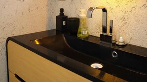 A bathroom with a black sink, a mirror, and a textured wall. - Kotimaailma Penthouse Studio (Lahti)