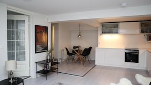 A modern kitchen with white cabinets, a built-in oven, and a microwave. - Kotimaailma Penthouse Studio (Lahti)