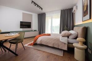 A modern hotel room with a bed, a desk, a chair, and a TV. - HUBIX - City of Mara Apartments (Timisoara)
