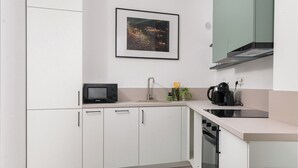 A modern kitchen with white cabinets, a microwave, a sink, and a stove.