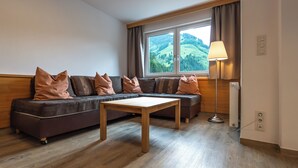 A modern living room with a sofa set, a wooden coffee table, and a floor lamp. - Appartements MaLo by we rent (Viehhofen)