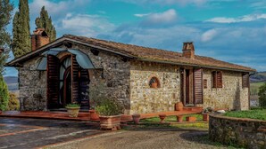Ein Haus aus Stein mit Ziegeldach, Holzläden und einem Schotterweg.