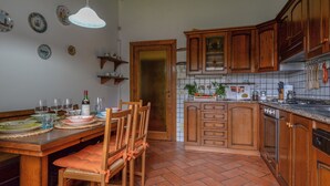 Eine Küche mit Holzausbau, einer gefliesten Spritzschutzwand und einem Essbereich mit Tisch für vier Personen.