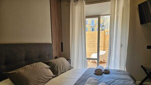 Ett hotellrum med en säng, kuddar och två hoprullade handdukar på sängen.