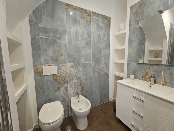 A bathroom with a bidet, toilet, and a vanity with a mirror. - Guest House Montegrappa Terrace by Be Your Home (Civitavecchia)