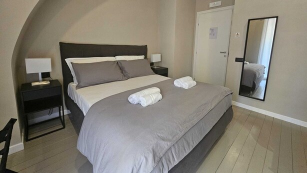 A neatly arranged bedroom with a bed, bedside tables, a mirror, and a wardrobe. - Guest House Montegrappa Terrace by Be Your Home (Civitavecchia)