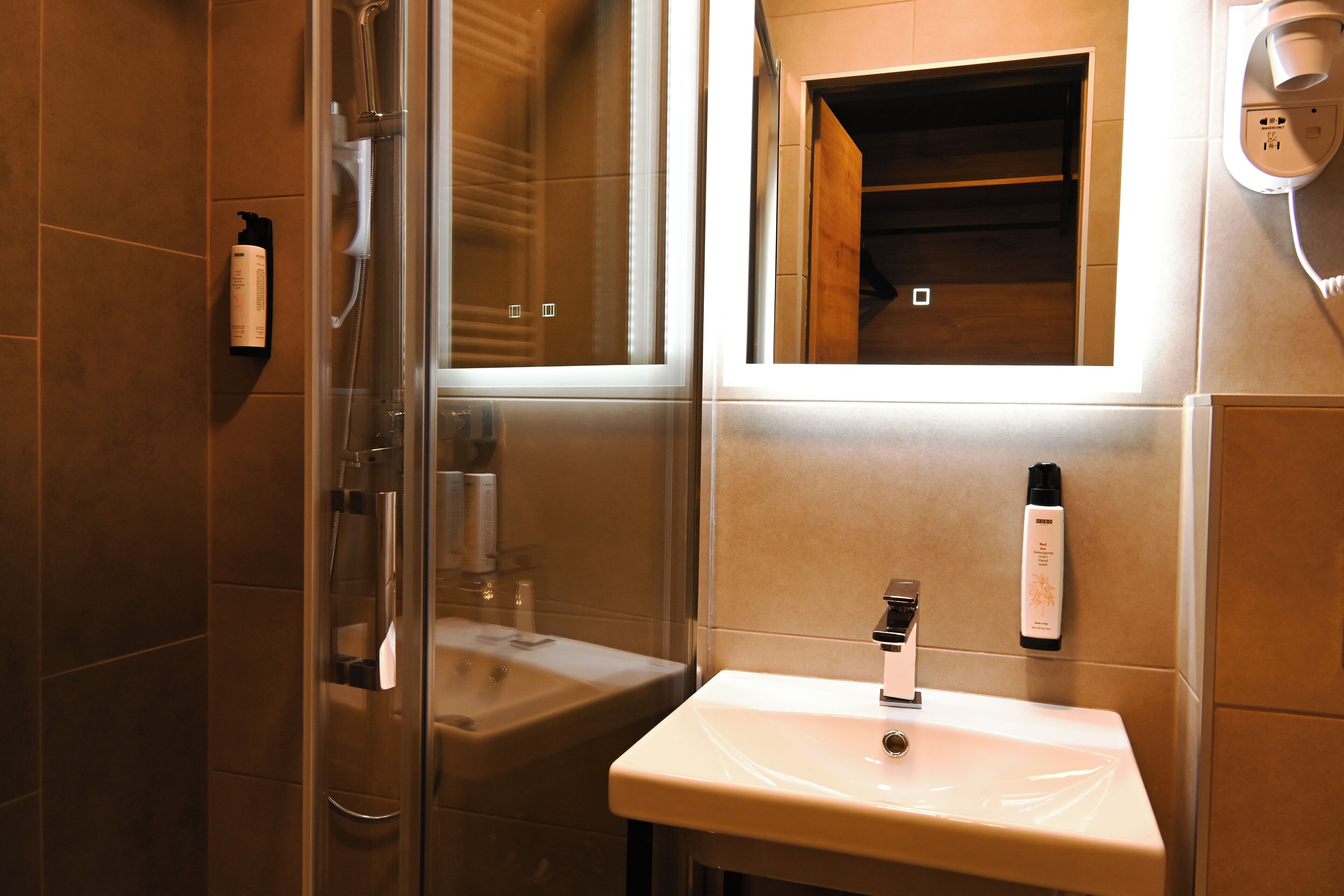 Une salle de bain avec une douche à parois de verre, un lavabo et un miroir.